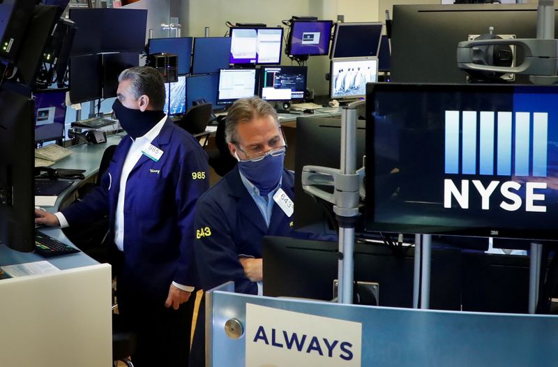 FILE PHOTO: Traders wearing masks work,on the floor at the New York Stock Exchange (NYSE) in New York, U.S., May 26, 2020. REUTERS/Brendan McDermid/File Photo
