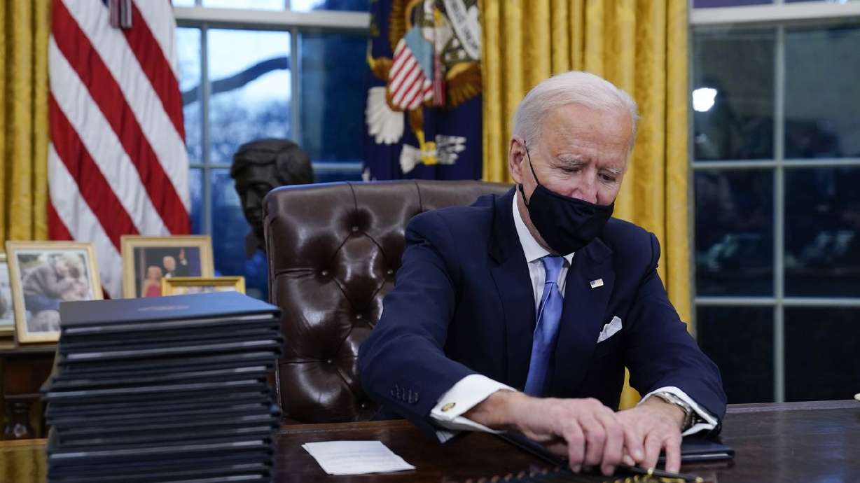 President Joe Biden reaches for a pen to sign his first
executive orders in the Oval Office of the White House in
Washington on Jan. 20, 2021.