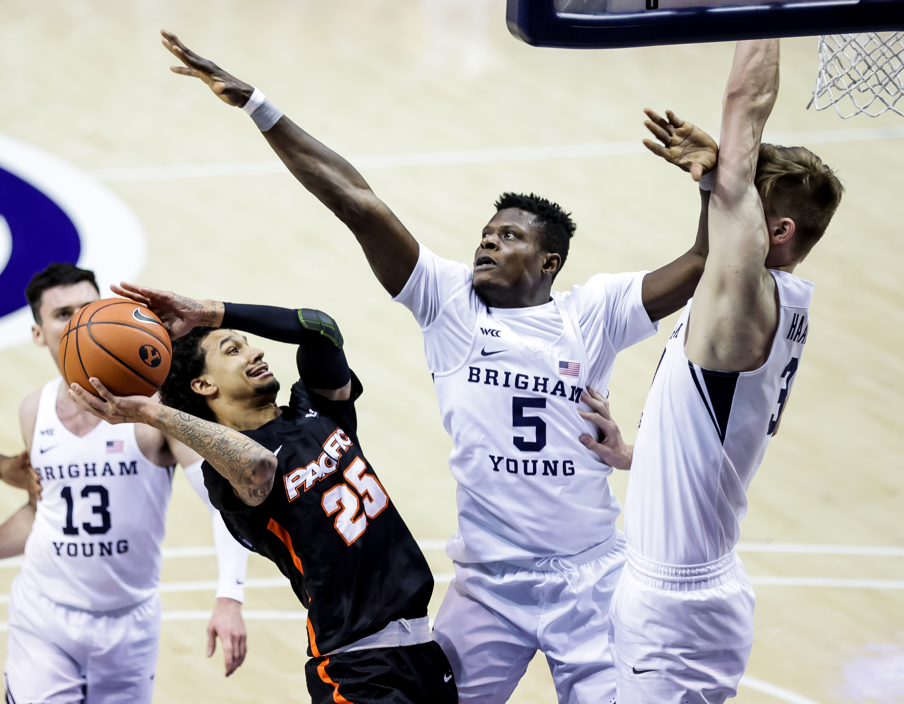 Pacific Tigers guard Justin Moore (25) goes to the hoop against Brigham Young Cougars forward Gideon George (5) and forward Matt Haarms (3) at the Marriott Center in Provo on Saturday, Jan. 30, 2021.