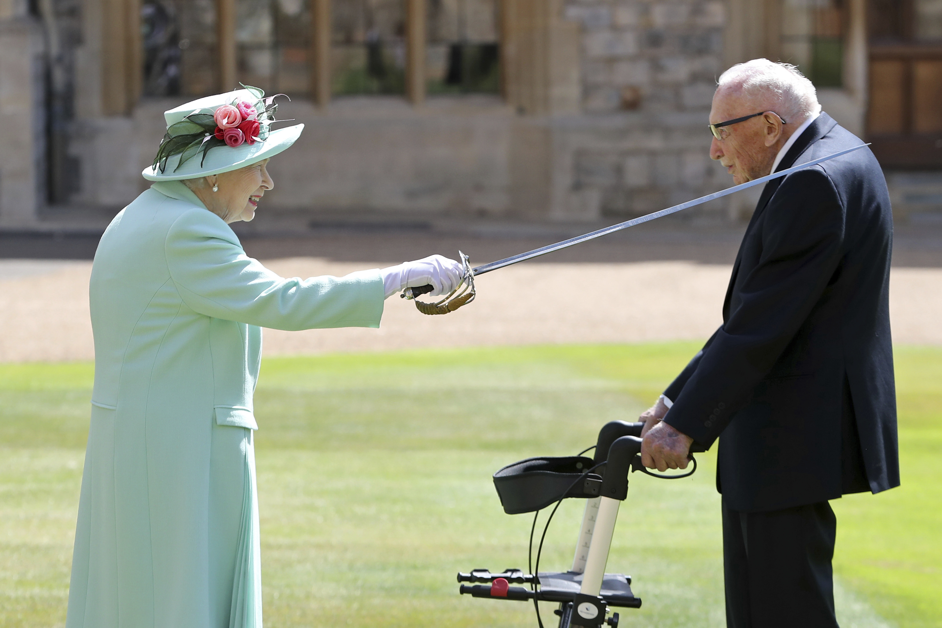 FILE - In this Friday, July 17, 2020 file photo, Captain Sir Thomas Moore receives his knighthood from Britain's Queen Elizabeth, during a ceremony at Windsor Castle in Windsor, England. Tom Moore, the 100-year-old World War II veteran who captivated the British public in the early days of the coronavirus pandemic with his fundraising efforts, has died, Tuesday Feb. 2, 2021. (Chris Jackson/Pool Photo via AP, File) [Feb-02-2021]