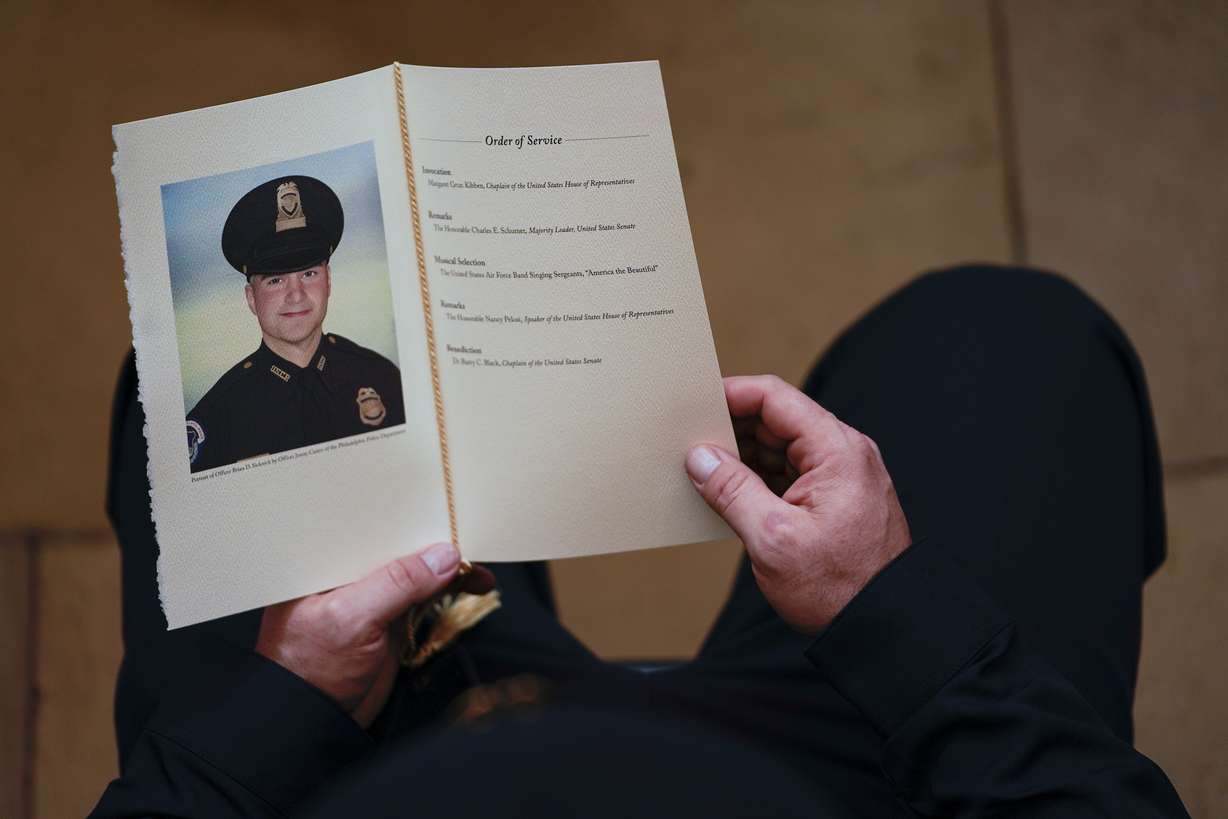 A U.S. Capitol Police Officer holds a program during a ceremony memorializing U.S. Capitol Police officer Brian Sicknick, as an urn with his cremated remains lies in honor on a black-draped table at the center of the Capitol Rotunda, Wednesday, Feb. 3, 2021, in Washington.