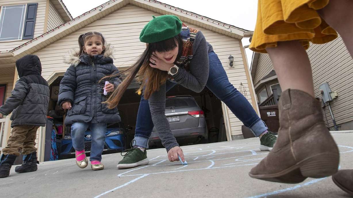 Tess Edwards draws a hopscotch grid with the children
she cares for at her home in Eagle Mountain on Friday, Feb. 5,
2021.
