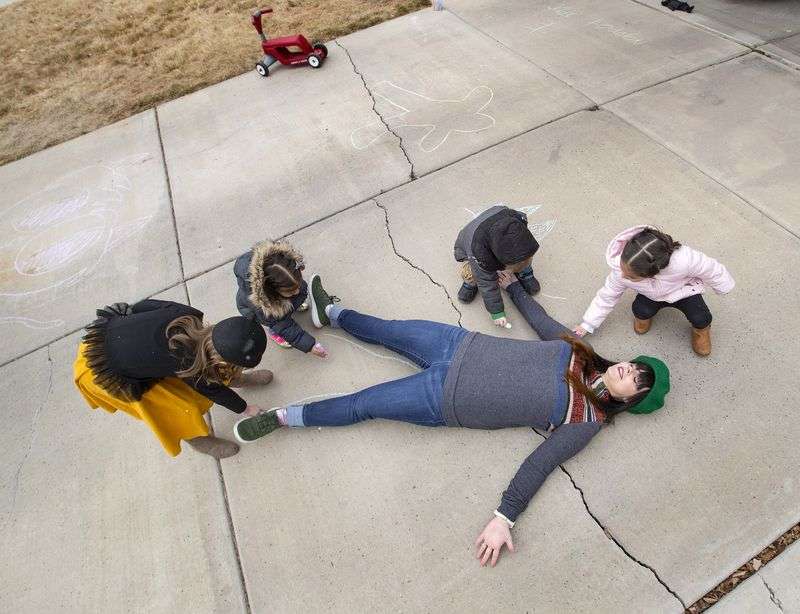 Tess Edwards smiles as Charey Campbell, left, Evelyn
Botello, Edwards’ son Porter Edwards and Camila Botello draw a
chalk outline of her in the driveway of her home day care in Eagle
Mountain on Friday, Feb. 5, 2021.
