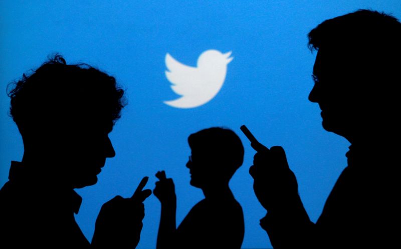 FILE PHOTO: People holding mobile phones are silhouetted against a backdrop projected with the Twitter logo in this illustration picture taken September 27, 2013. REUTERS/Kacper Pempel/Illustration