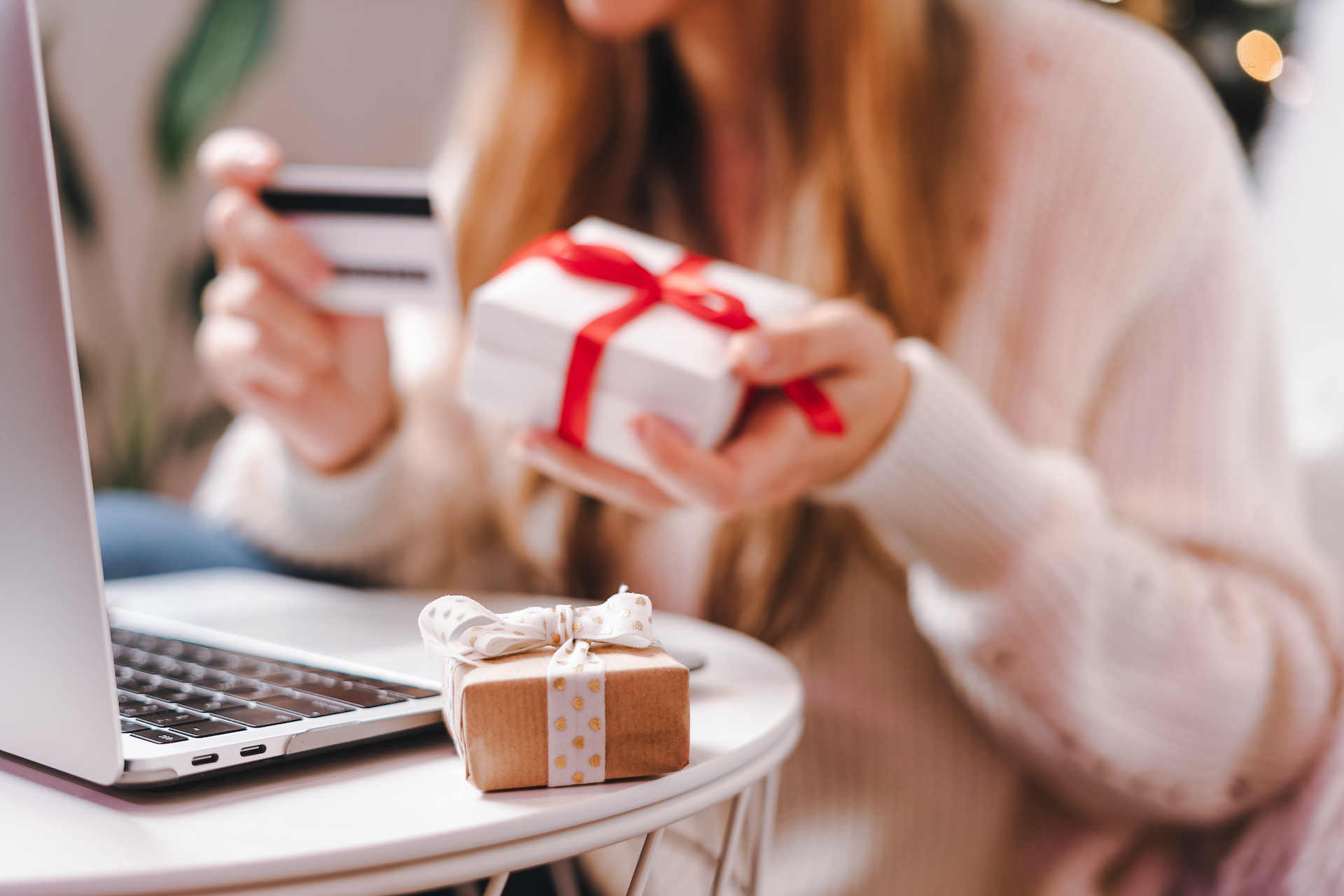 Close up of woman hands with credit card, gifts and laptop. Online shopping at Christmas, valentine day or birthday holidays. Freelance girl woking from home office
