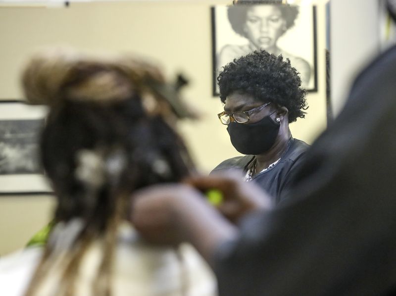 Yunia Jada, a licensed stylist, braids a clients dreadlocks at Ebony & Ivory hair salon in South Salt Lake on Thursday, Feb. 11, 2021.