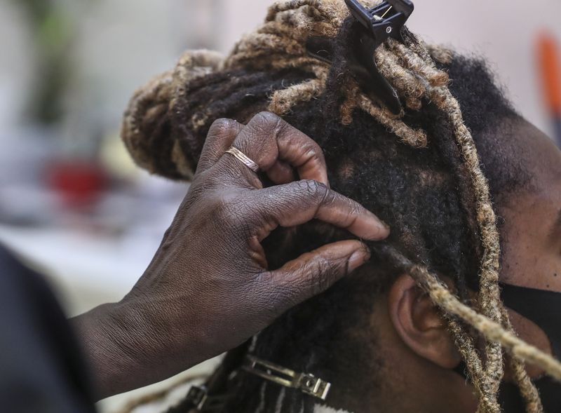 Yunia Jada, a licensed stylist, braids a client’s dreadlocks at Ebony & Ivory hair salon in South Salt Lake on Thursday, Feb. 11, 2021.