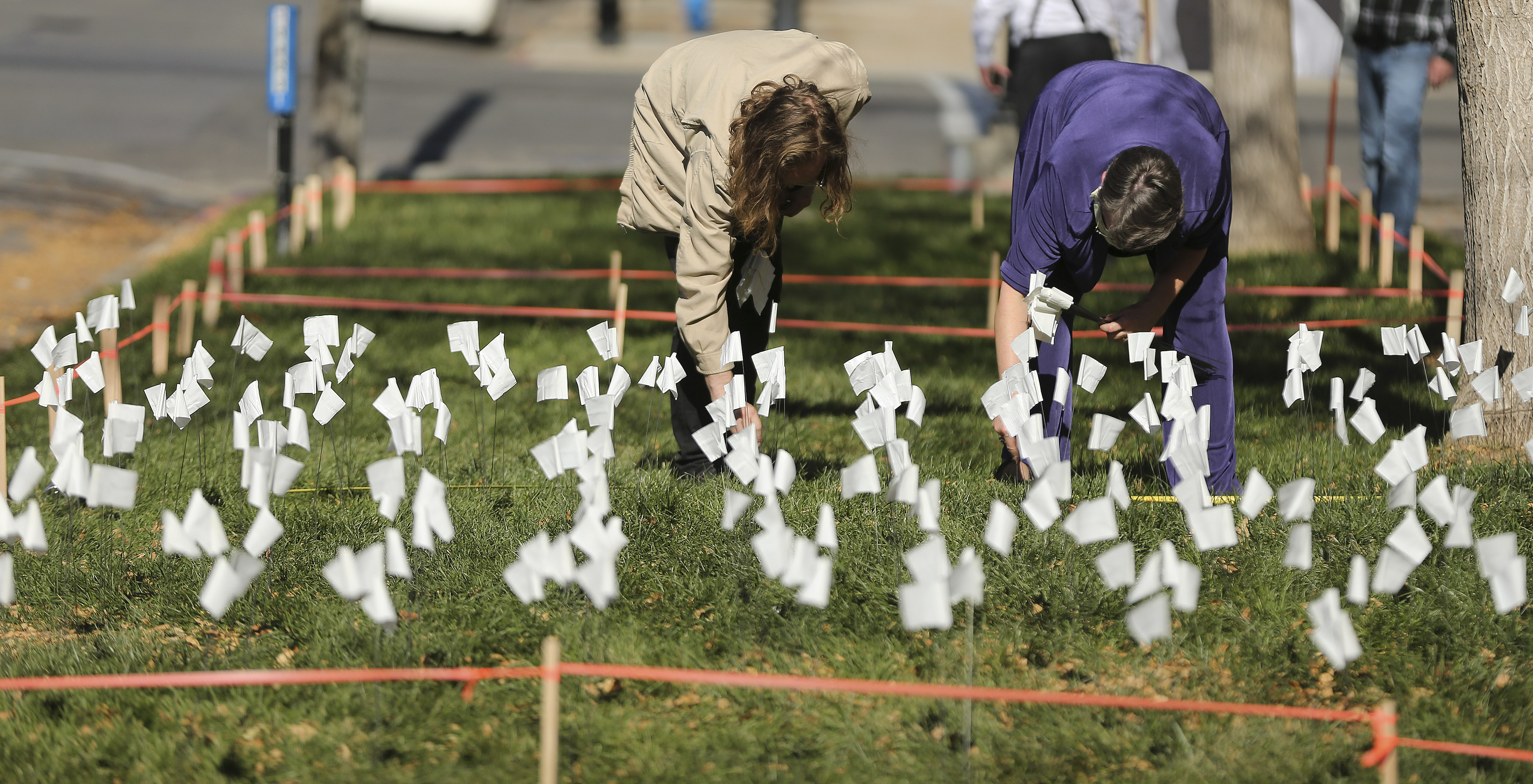 First United Methodist members Aaron Goll and Becky Buxton places flags in near the church in Salt Lake City on Sunday, Nov. 1, 2020, to honor those who have died from COVID-19 in Utah.