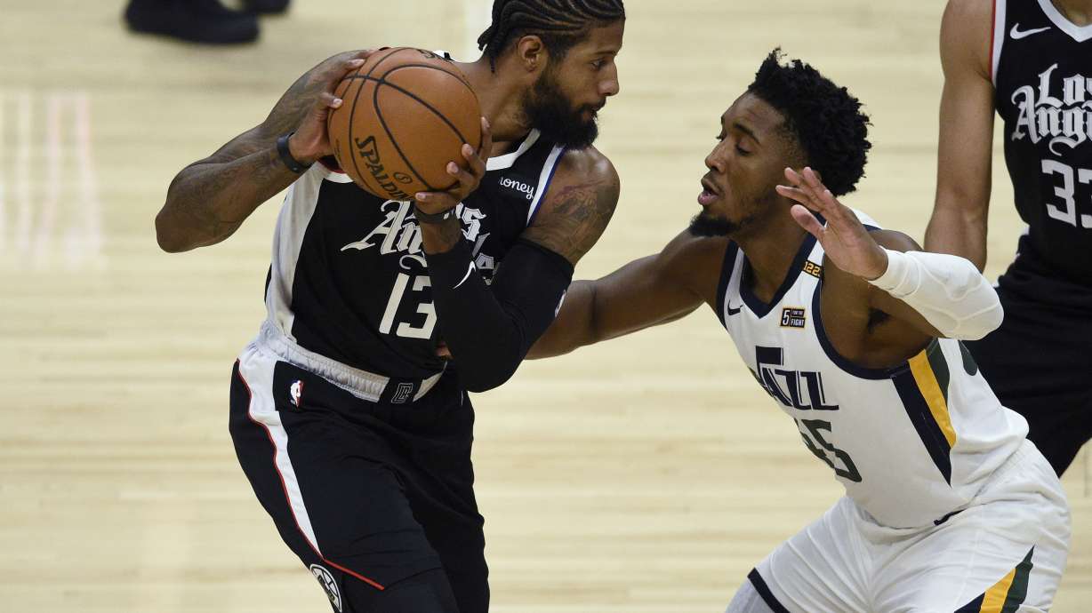 Los Angeles Clippers guard Paul George, left, holds on to the ball while Utah Jazz guard Donovan Mitchell defends during the first half of an NBA basketball game in Los Angeles, Friday, Feb. 19, 2021. (AP Photo/Kelvin Kuo)