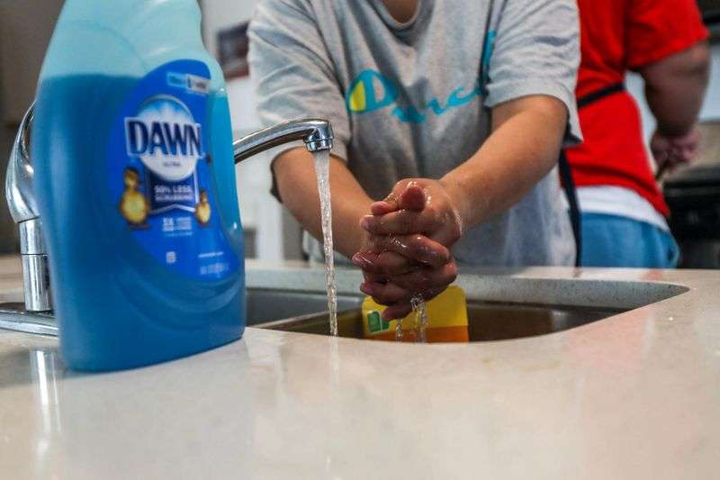 Lola Savaiinaea, an owner of SaWrap, a microenterprise
home kitchen, washes her hands before preparing food to sell in
Provo on Thursday, Feb. 18, 2021.