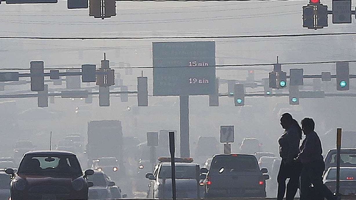 Pedestrians cross 300 West in Salt Lake City with smog
visible in the background in 2015. A bill working its way through
the state Capitol would step up Utah’s game on teleworking during
bad air days.
