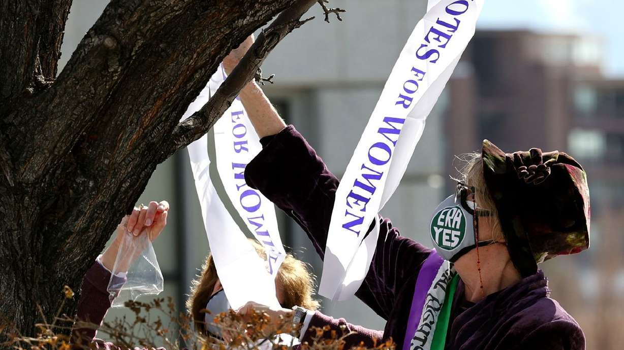 Robin Hough and others hang sashes from the branches of
a tree as supporters of the Equal Rights Amendment gather for a
rally at the Capitol in Salt Lake City on Tuesday, March 2, 2021.