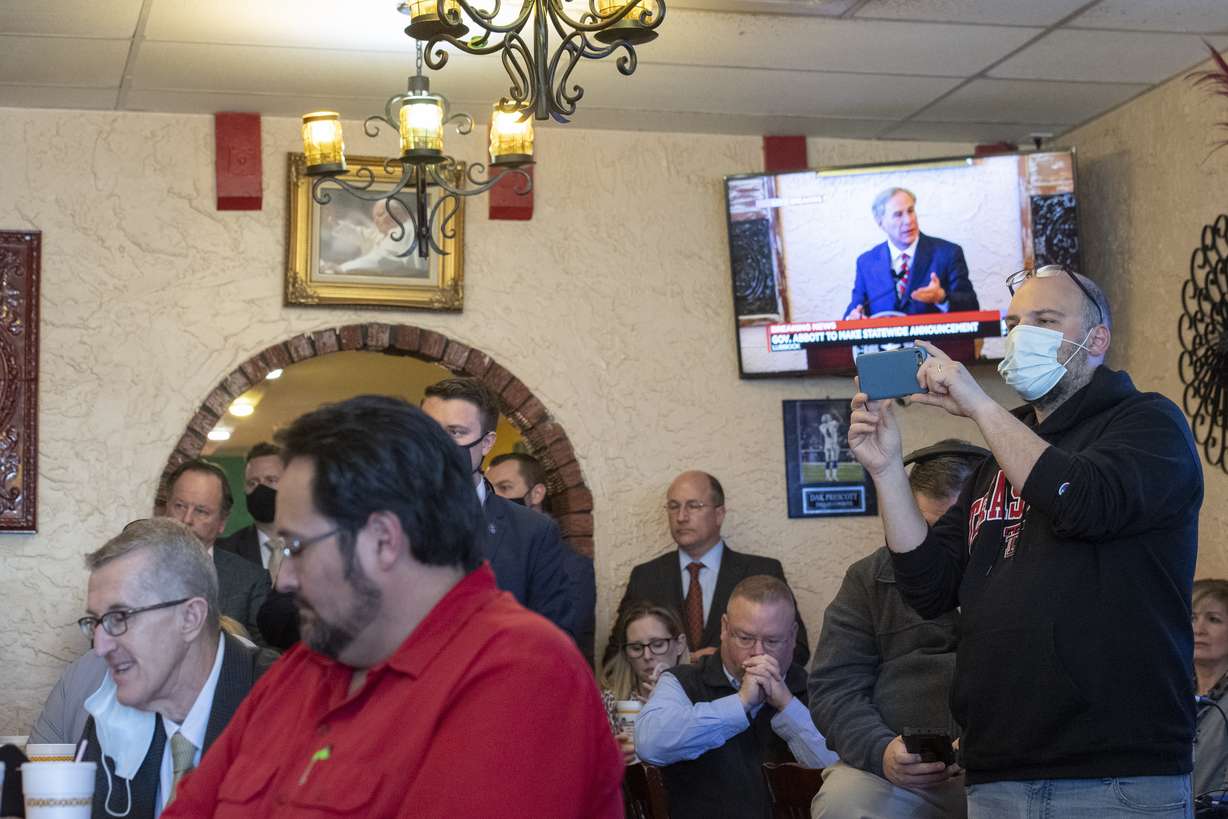 Texas Gov. Greg Abbott delivers an announcement, broadcasted on the TV in the background, as a crowd watches him make it at Montelongo's Mexican Restaurant on Tuesday, March 2, 2021, in Lubbock, Texas. Governor Abbott announced that he is rescinding executive orders that limit capacities for businesses and the statewide mask mandate.