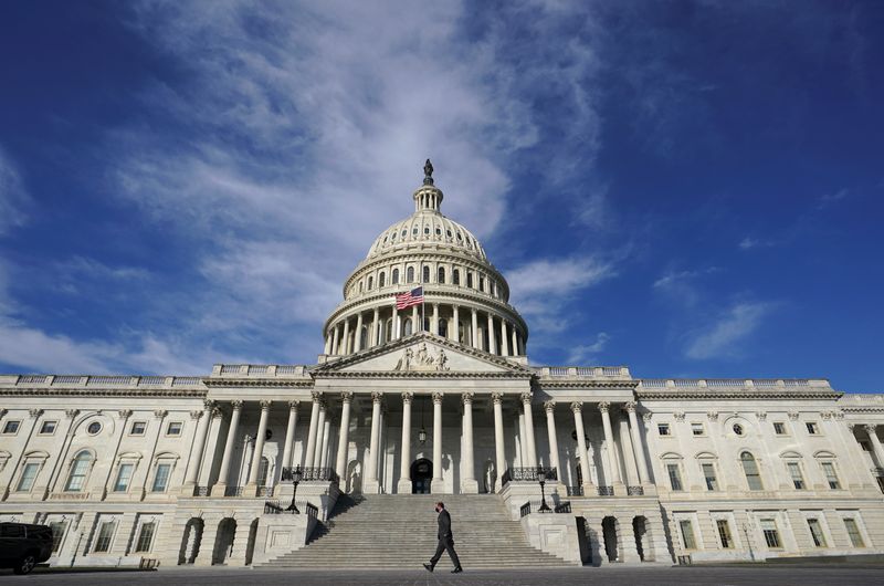 FILE PHOTO: A man makes his way past the U.S. Capitol on the day the House of Representatives is expected to vote on legislation to provide $1.9 trillion in new coronavirus relief in Washington, U.S., Feb. 26, 2021. REUTERS/Kevin Lamarque
