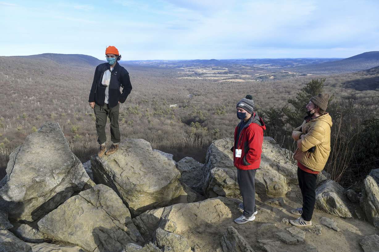 Keilan Barber, of West Chester, Pa., left, Christian Martella, center, and Ben Savitz, both of Havertown, Pa., hang out on the rocks at the South Lookout after hiking at Hawk Mountain Sanctuary in Kempton, Pa., in this Sunday, Jan. 24, 2021, file photo. During the pandemic, people around the world sought relief from lock downs and working from home in leisure sports.