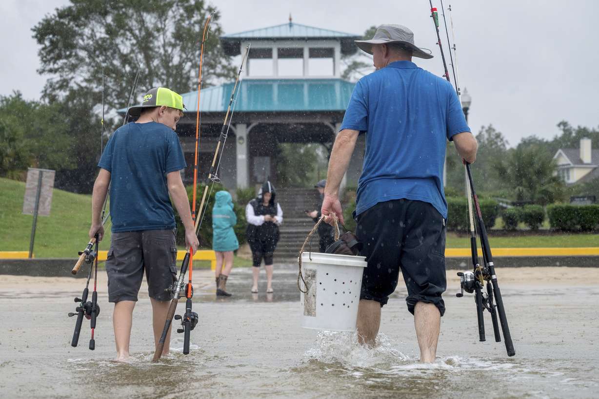 FILE - A father and son walk through the Hurricane Sally tidal surge in Ocean Springs, Miss., to fish on the beach, in this Tuesday, Sept. 15, 2020, file photo. During the pandemic, people around the world sought relief from lock downs and working from home in leisure sports.