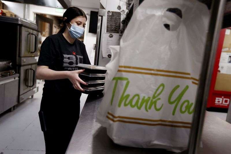 Maddie Evans, of BD Catering in Syracuse, places warm meals into a bag to be delivered for domestic violence victims on Friday, March 12, 2021.