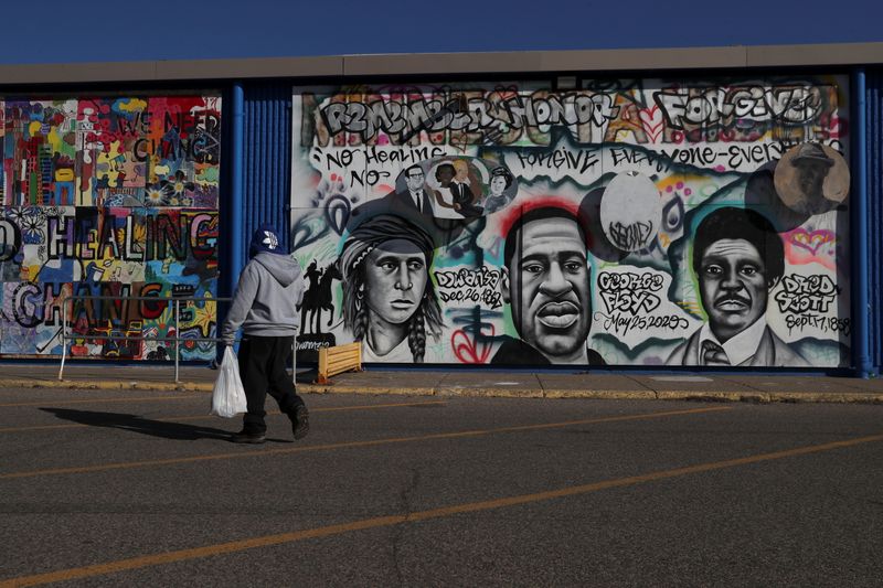 A pedestrian walks past community murals painted on the side of what was the Lake Street Kmart, which was destroyed in the wake of George Floyd’s death, as jury selection continues in the trial of former Minneapolis police officer Derek Chauvin, on murder charges in the death of George Floyd in Minneapolis, Minnesota, U.S., March 12, 2021. Picture taken March 12, 2021. REUTERS/Leah Millis