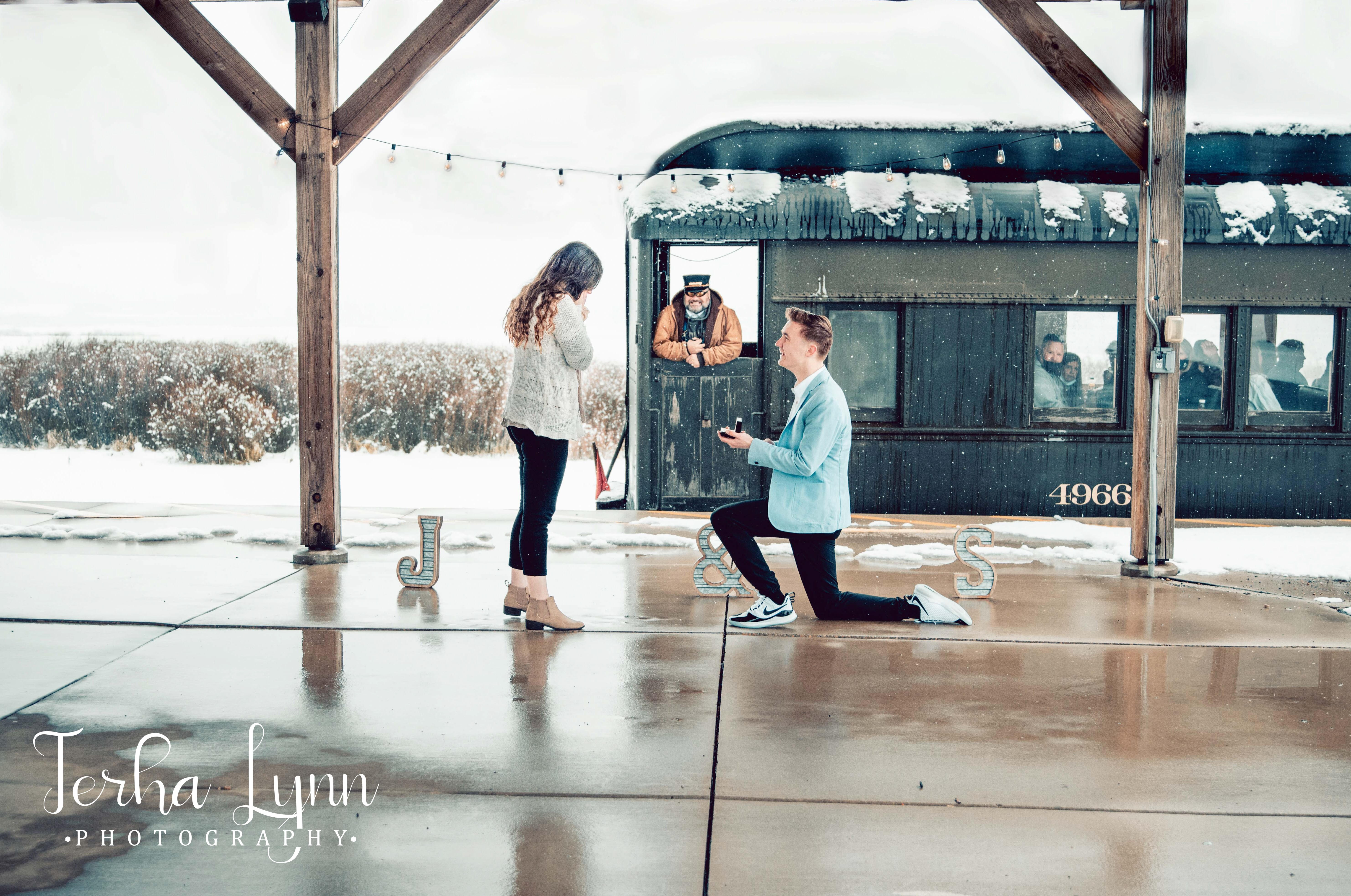 Jared Hughes kneels down to propose to Sariah Harker on March 11 as  Heber Valley Railroad Conductor Brandon Crose passes through.