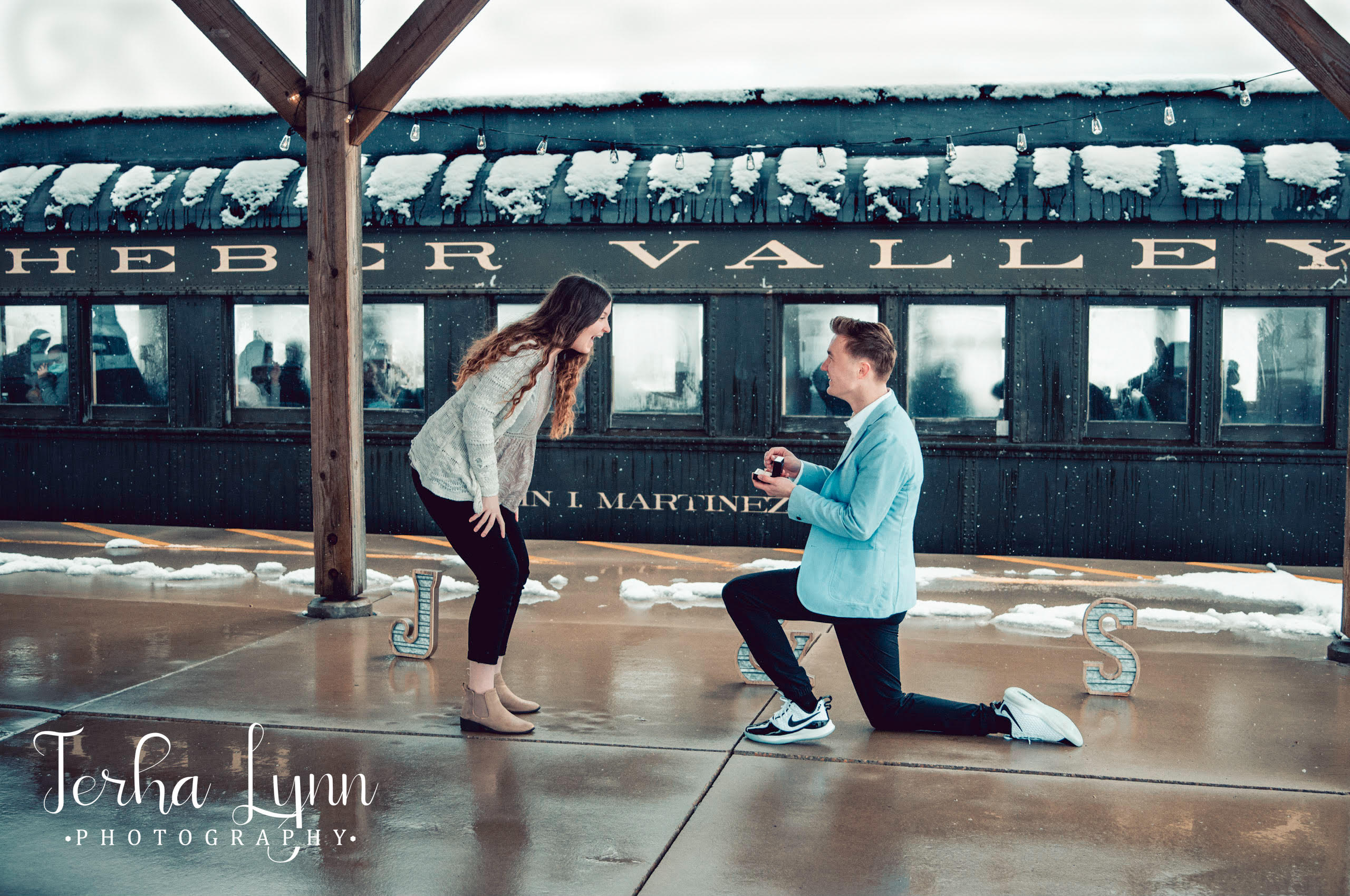 Jared Hughes knelt down on one knee to propose to Sariah Harker prior to Heber Valley Railroad Conductor Brandon Crose passing through.