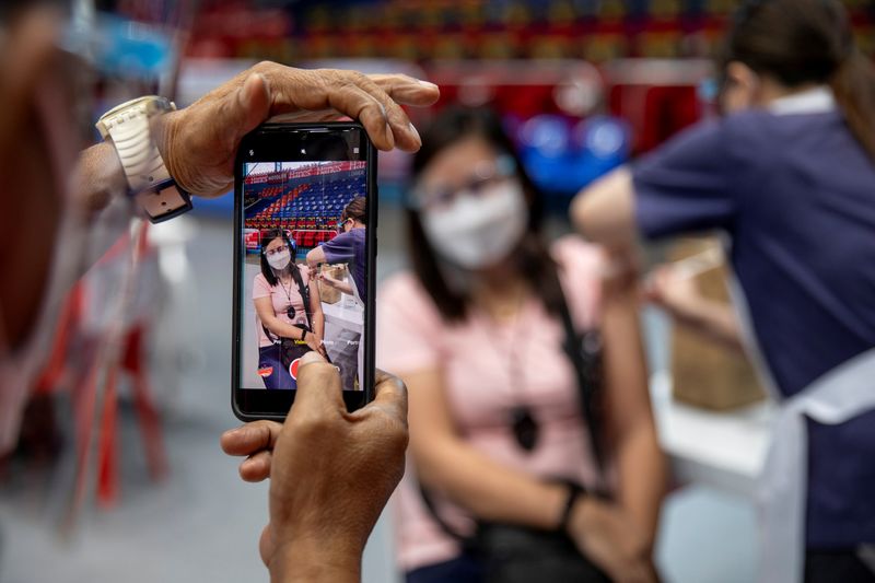 FILE PHOTO: A healthcare worker documents his colleague getting inoculated with a coronavirus disease (COVID-19) vaccine at San Juan City, Metro Manila, Philippines, March 23, 2021. REUTERS/Eloisa Lopez
