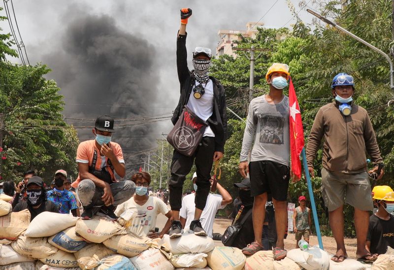People stand on a barricade during a protest against the military coup, in Yangon, Myanmar March 27, 2021.