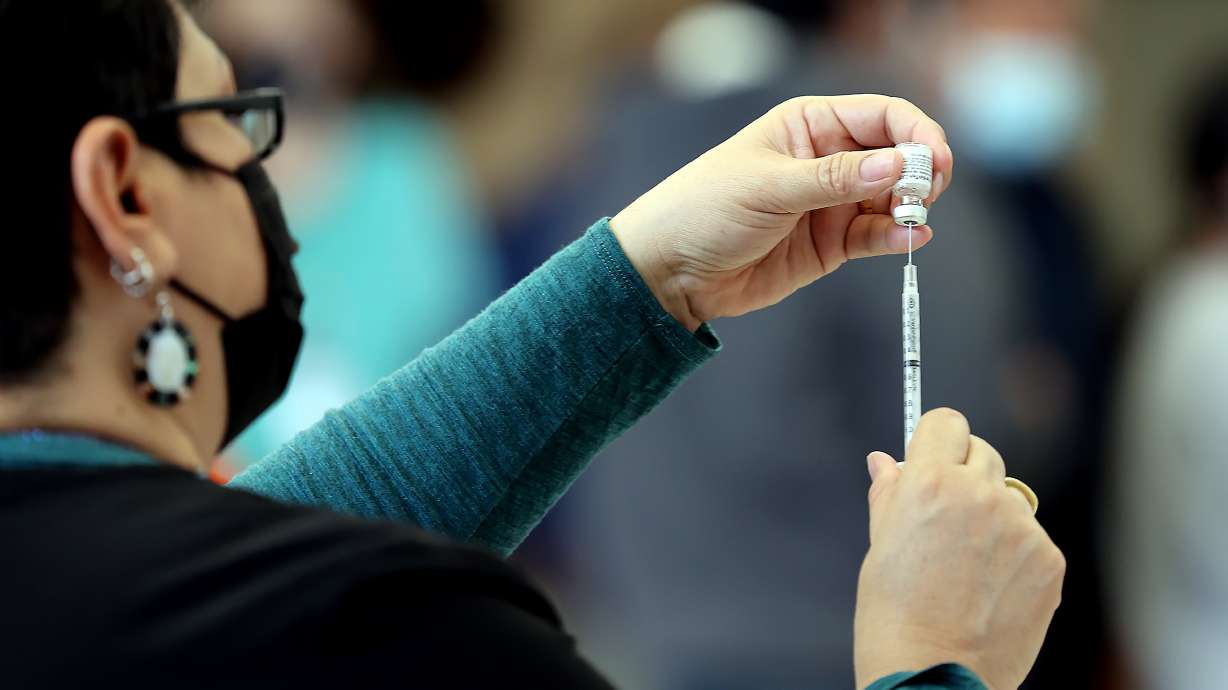 A worker prepares a dose of a COVID-19 vaccine at a vaccination clinic at the North Davis Senior Center in Clearfield on Friday, March 26, 2021, as Sen. Mitt Romney, R-Utah, and Lt. Gov. Deidre Henderson toured the site