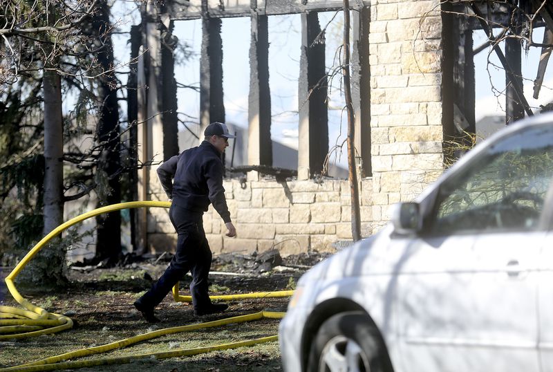 A Kaysville firefighter works at the scene of a house
fire in Kaysville on Wednesday, March 31, 2021.
