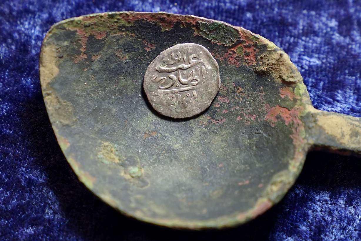 A 17th-century Arabian silver coin that research shows was struck in 1693 in Yemen, rests in a 17th-century brass spoon on a table, in Warwick, R.I., Thursday, March 11, 2021. The coin was found at a farm, in Middletown, R.I., in 2014 by metal detectorist Jim Bailey, who contends it was plundered in 1695 by English pirate Henry Every from Muslim pilgrims sailing home to India after a pilgrimage to Mecca.