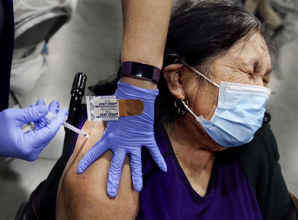 Albina Reyes, of Salt Lake City, winces as she receives a COVID-19 vaccination at the Mountain America Exposition Center in Sandy on Thursday, Feb. 11, 2021.