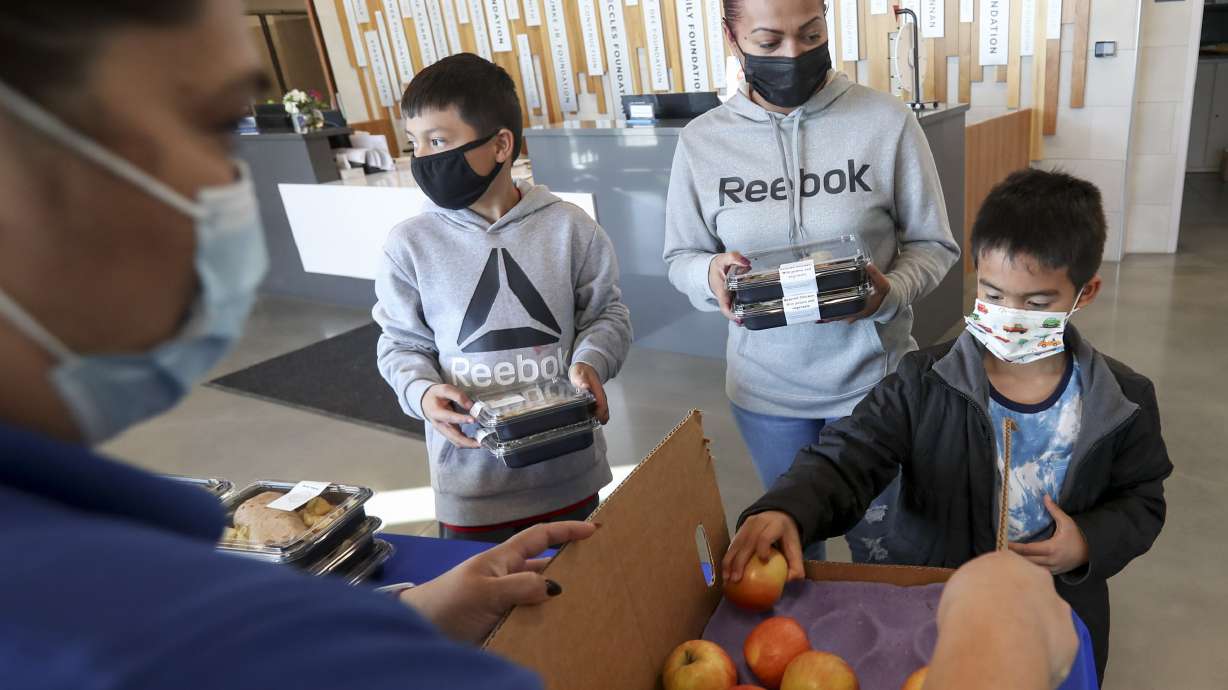 Heidy Melgar, center, grabs some dinner after picking up sons Mario, left, and Julian from Neighborhood House in Salt Lake City on Tuesday, March 30, 2021. Neighborhood House provides preschool, youth programs and adult care for its clients and is participating in the Nourish to Flourish initiative where local restaurants, funded by community members, prepare food for organizations serving under-resourced groups.