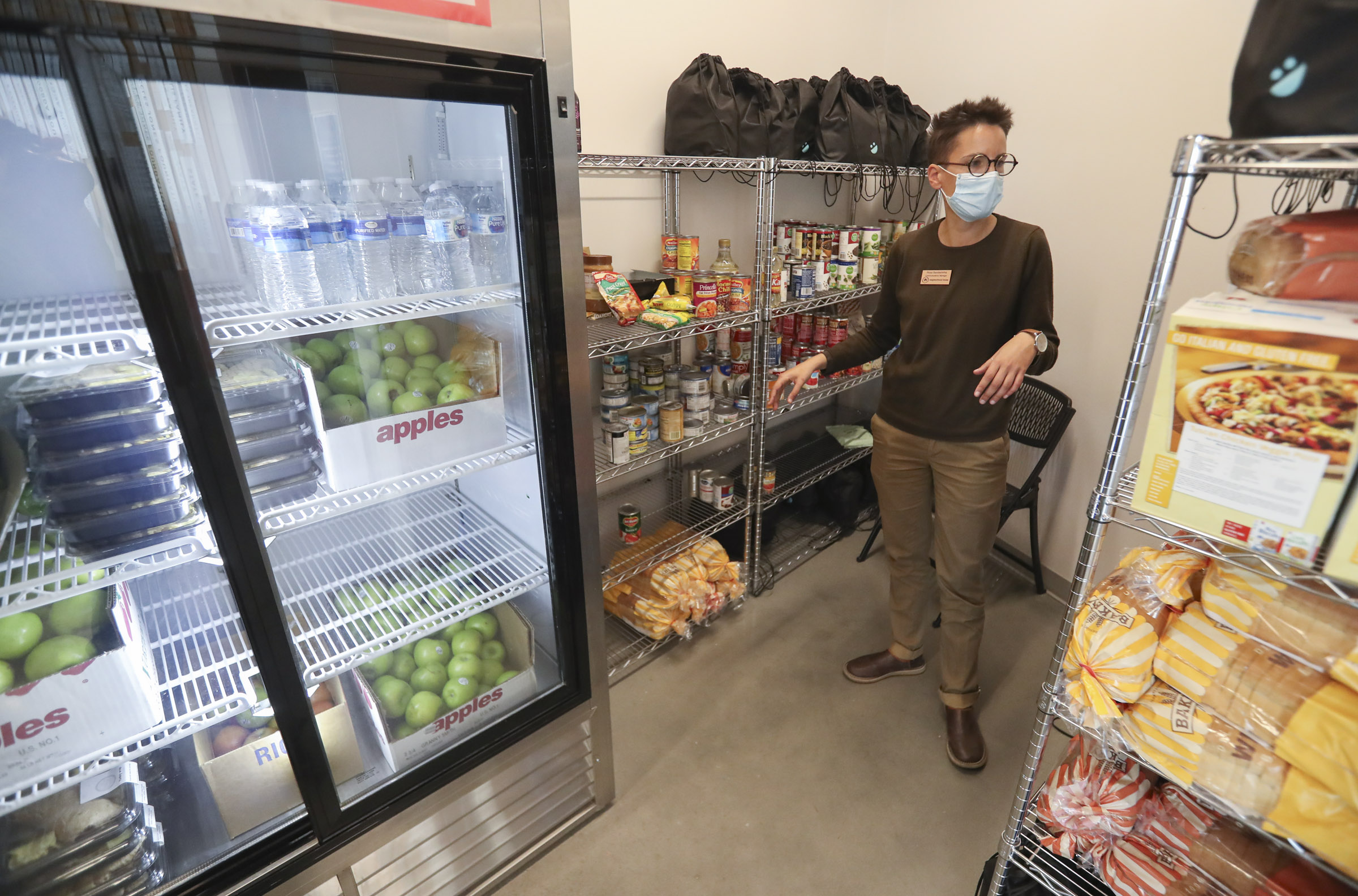 Rosa Bandeirinha, communications manager for Neighborhood House, organizes food in the pantry at the organization's Salt Lake City location on Tuesday, March 30, 2021. Neighborhood House provides preschool, youth programs and adult care for its clients and is participating in the Nourish to Flourish initiative, where local restaurants, funded by community members, prepare food for organizations serving under-resourced groups.