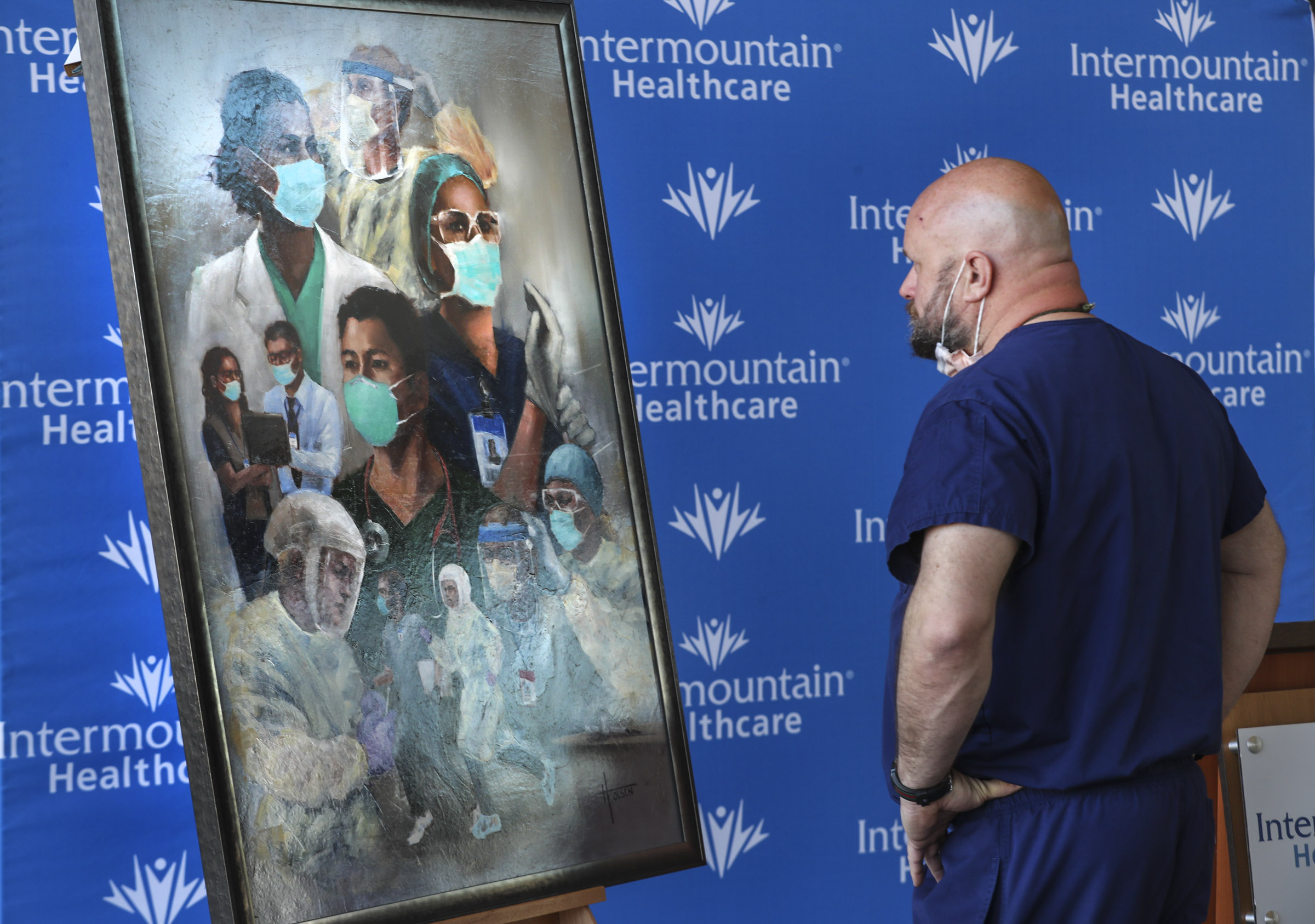 Jay Larsen, an Intermountain Healthcare emergency department nurse, looks at Utah artist Heather Olsen's painting "Together We Can Do This" after it was presented to caregivers at the Intermountain Transformation Center in Murray on Monday, April 5, 2021. Olsen painted the work to honor Utah caregivers for their dedication, commitment and heroics in saving countless lives during the pandemic. Copies of the painting will be displayed in Intermountain hospitals across the state.