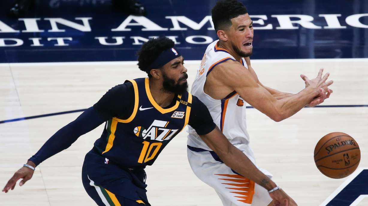 Utah Jazz guard Mike Conley (10) blocks the dribble from Phoenix Suns guard Devin Booker (1) during an NBA basketball game at Vivint Smart Home Arena in Salt Lake City on Thursday, Dec. 31, 2020.
