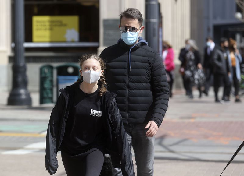 Sophia Cline, left, and Brent Cline wear masks while
walking in downtown Salt Lake City on Wednesday, March 24,
2021.