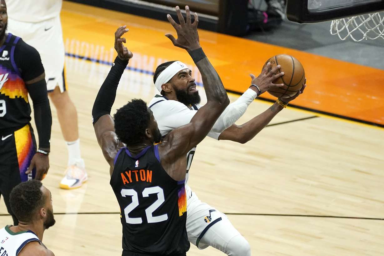 Utah Jazz guard Mike Conley shoots as Phoenix Suns center Deandre Ayton (22) defends during the second half of an NBA basketball game, Wednesday, April 7, 2021, in Phoenix.