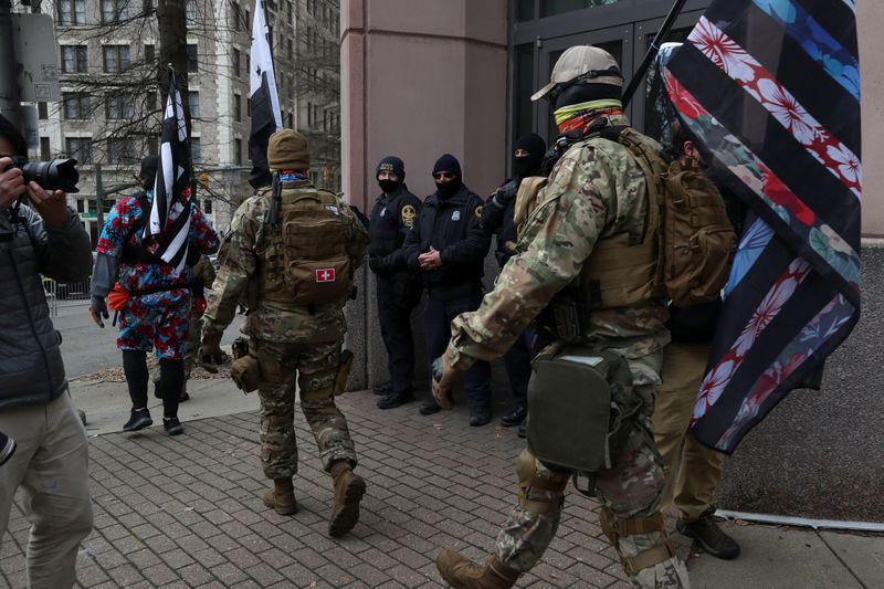 FILE PHOTO: Armed individuals carrying insignia associated with the Boogaloo Movement walk in front of law enforcement officers as media members photograph them outside the Capitol Building of Virginia, in Richmond, Virginia, U.S. January 18, 2021. REUTERS/Leah Millis