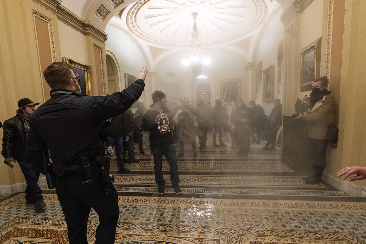 FILE - In this Jan. 6, 2021, file photo, smoke fills the walkway outside the Senate Chamber as violent rioters loyal to President Donald Trump are confronted by U.S. Capitol Police officers inside the Capitol in Washington.