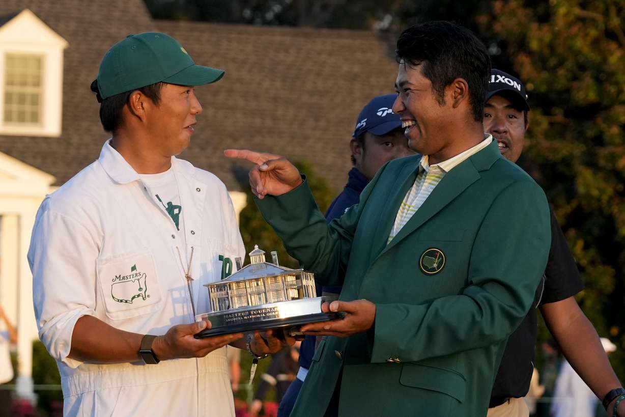 Hideki Matsuyama, of Japan, holds his trophy with his caddie Shota Hayafuji after winning the Masters golf tournament on Sunday, April 11, 2021, in Augusta, Ga.
