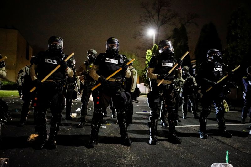 Officers stand guard outside Brooklyn Center Police Department with trash thrown at them by demonstrators at their feet after police allegedly shot and killed a man, who local media report is identified by the victim's mother as Daunte Wright, in Brooklyn Center, Minnesota, U.S., April 11, 2021. REUTERS/Nick Pfosi