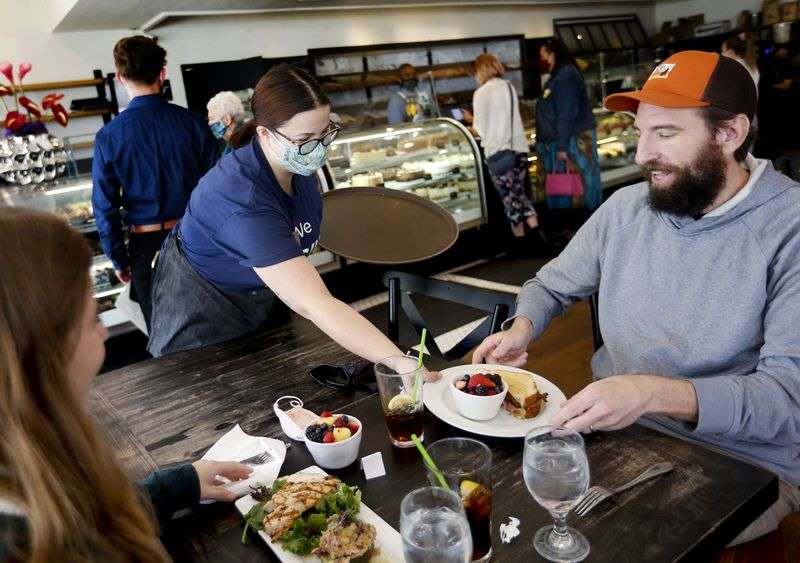 Eloise Schmitt serves lunch to Emma Larsen and her
father, Shawn, at Gourmandise in Salt Lake City on Thursday, April
8, 2021. Despite record numbers of Utahns filing for jobless
benefits every week, some Utah employers are having trouble finding
workers to fill open positions.