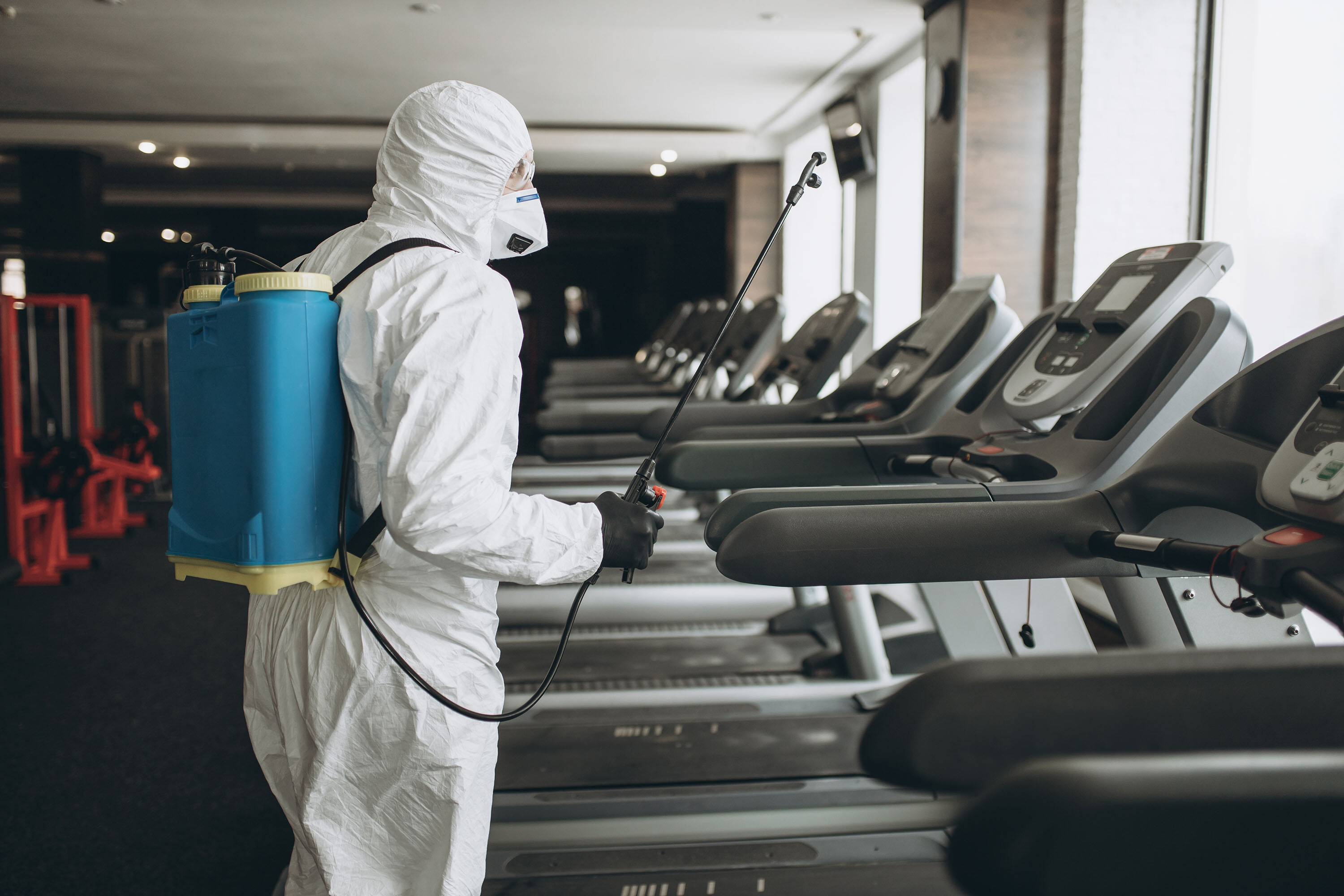 A worker in a protective suit cleans exercise equipment. The Centers for Disease Control, on Monday, April 19, 2021, said the risk of surface transmission of Covid-19 is low.