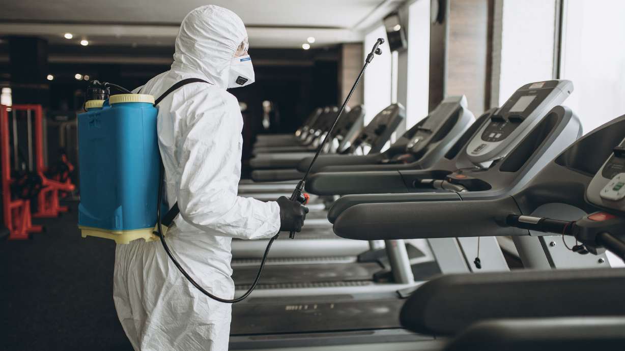 A worker in a protective suit cleans exercise equipment. The Centers for Disease Control, on Monday, April 19, 2021, said the risk of surface transmission of Covid-19 is low.
