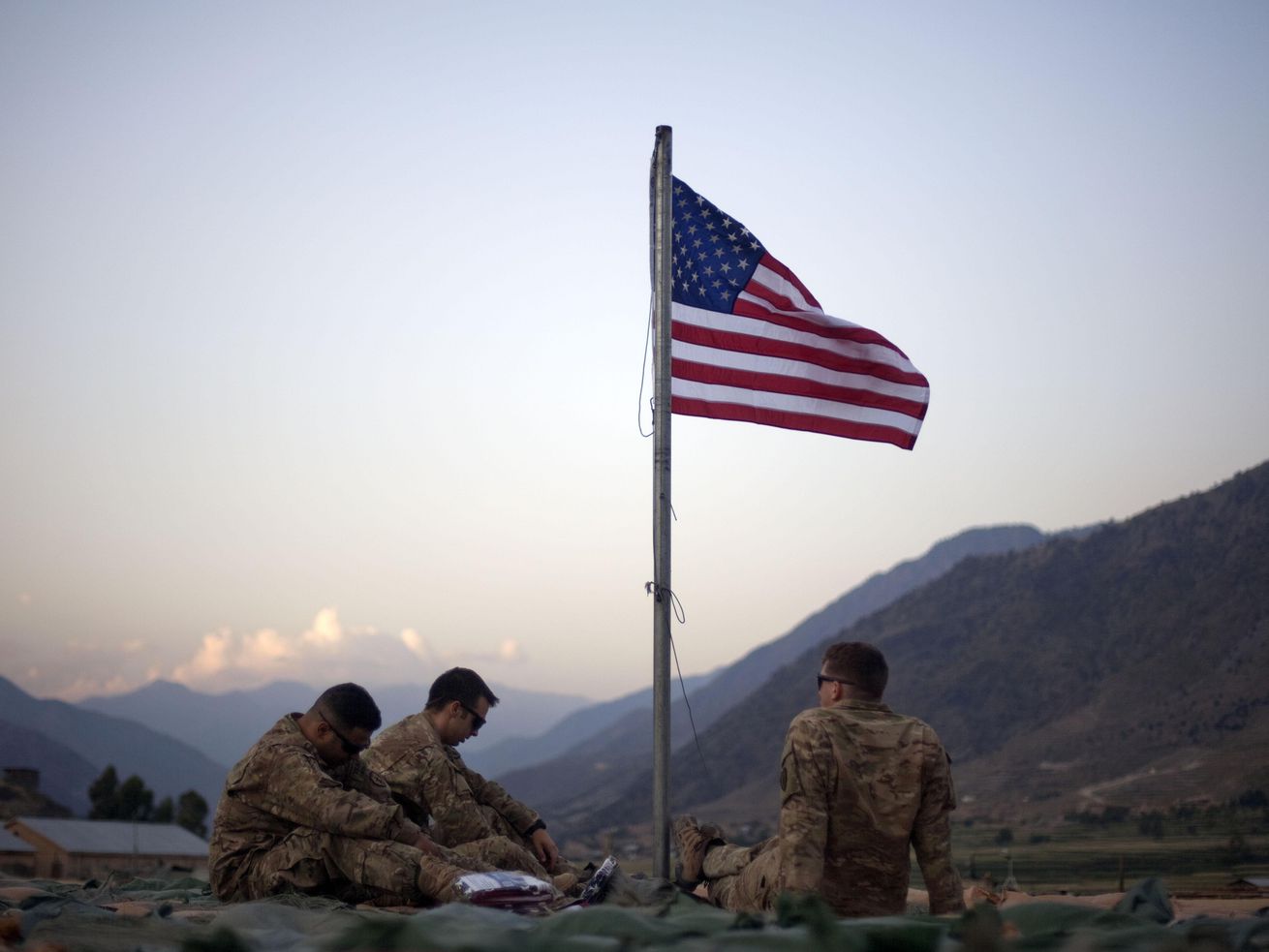 In this Sept. 11, 2011 file photo, US soldiers sit
beneath an American flag just raised to commemorate the tenth
anniversary of the 9/11 attacks at Forward Operating Base Bostick
in Kunar province, Afghanistan.