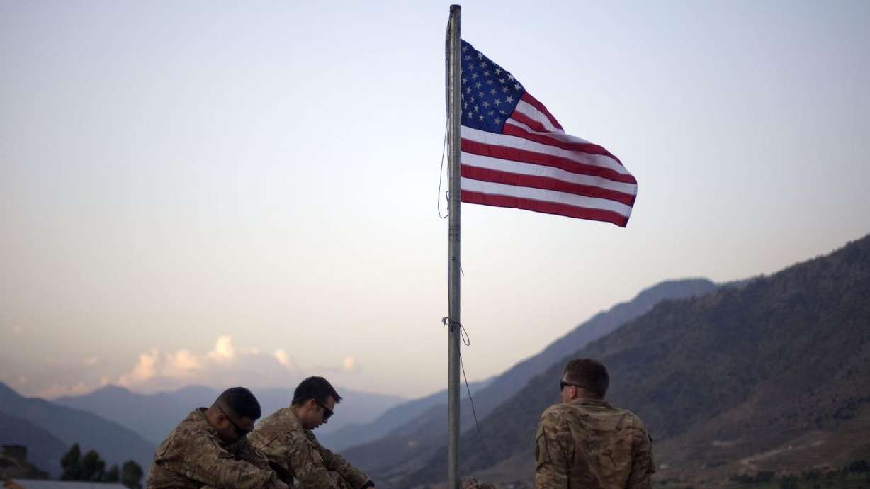 In this Sept. 11, 2011 file photo, US soldiers sit
beneath an American flag just raised to commemorate the tenth
anniversary of the 9/11 attacks at Forward Operating Base Bostick
in Kunar province, Afghanistan.