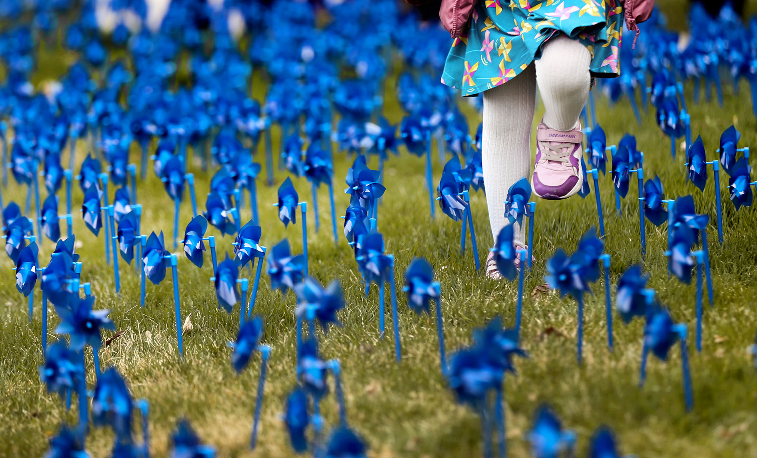 A child walks through a field of blue pinwheels that were planted in honor of every child who was abused in Salt Lake County during 2020 at the Salt Lake County Government Center in Salt Lake City on Wednesday, April 21, 2021. In Salt Lake County alone there were 3,616 confirmed cases of child abuse last year.