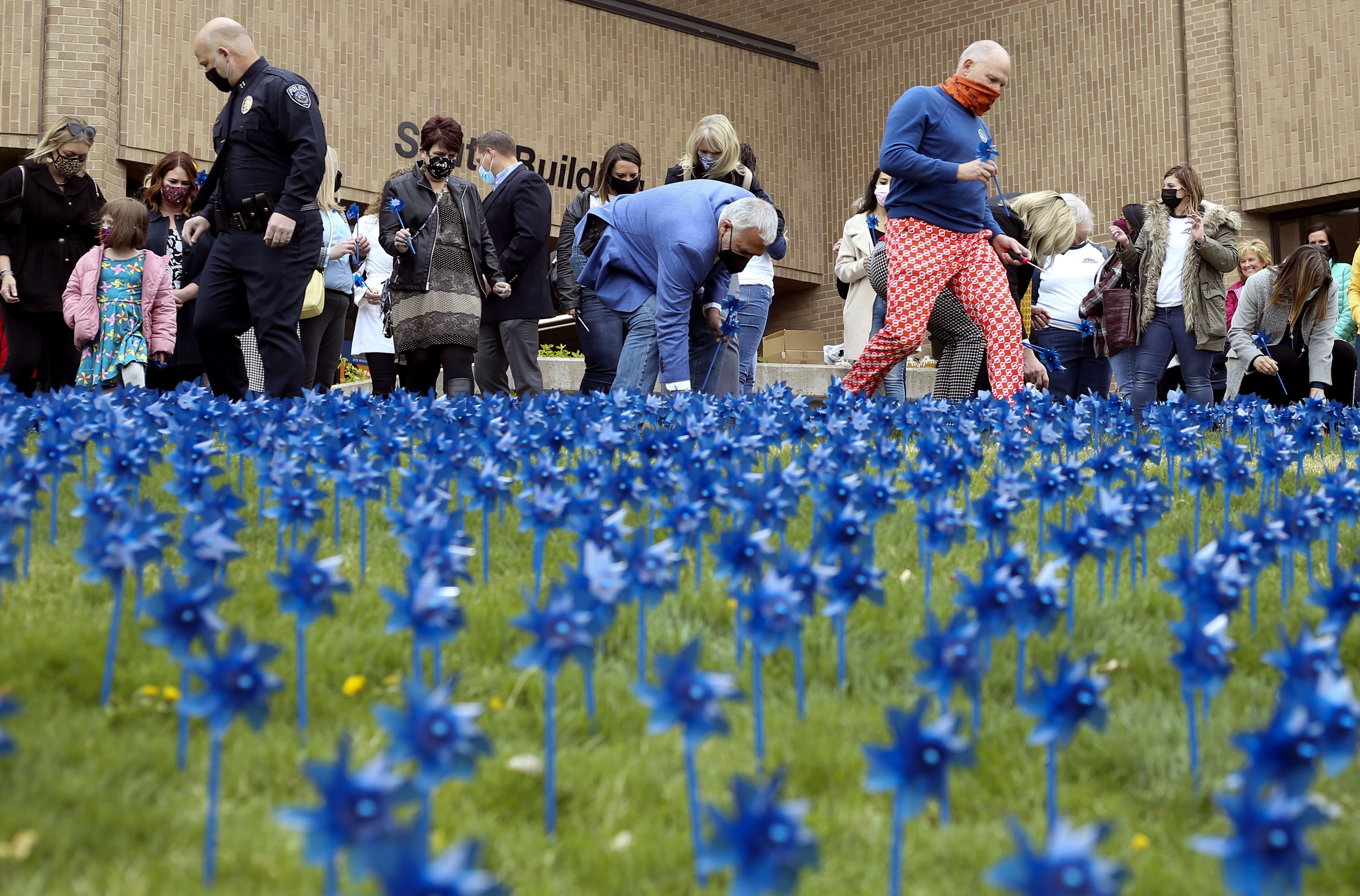 People plant 3,616 blue pinwheels in honor of every child who was abused in Salt Lake County during 2020 at the Salt Lake County Government Center in Salt Lake City on Wednesday, April 21, 2021. Blue pinwheels are the national symbol of child abuse prevention month.