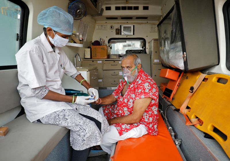 A paramedic uses an oximeter to check the oxygen level of a patient inside an ambulance while waiting to enter a COVID-19 hospital for treatment, amidst the spread of the coronavirus disease (COVID-19) in Ahmedabad, India, April 22, 2021. REUTERS/Amit Dave