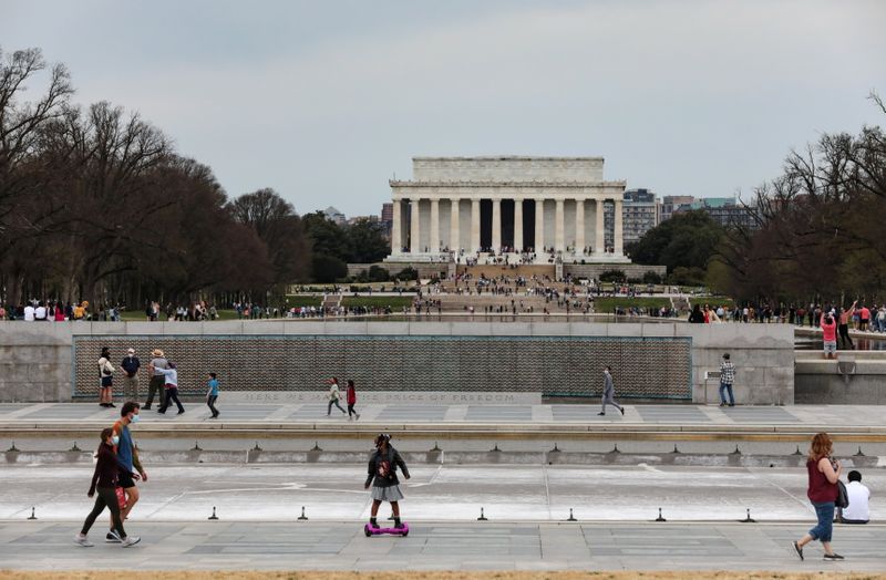 FILE PHOTO: People enjoy the warm weather at the World War II Memorial near the Lincoln Memorial, in Washington, U.S. March 27, 2021. REUTERS/Cheriss May
