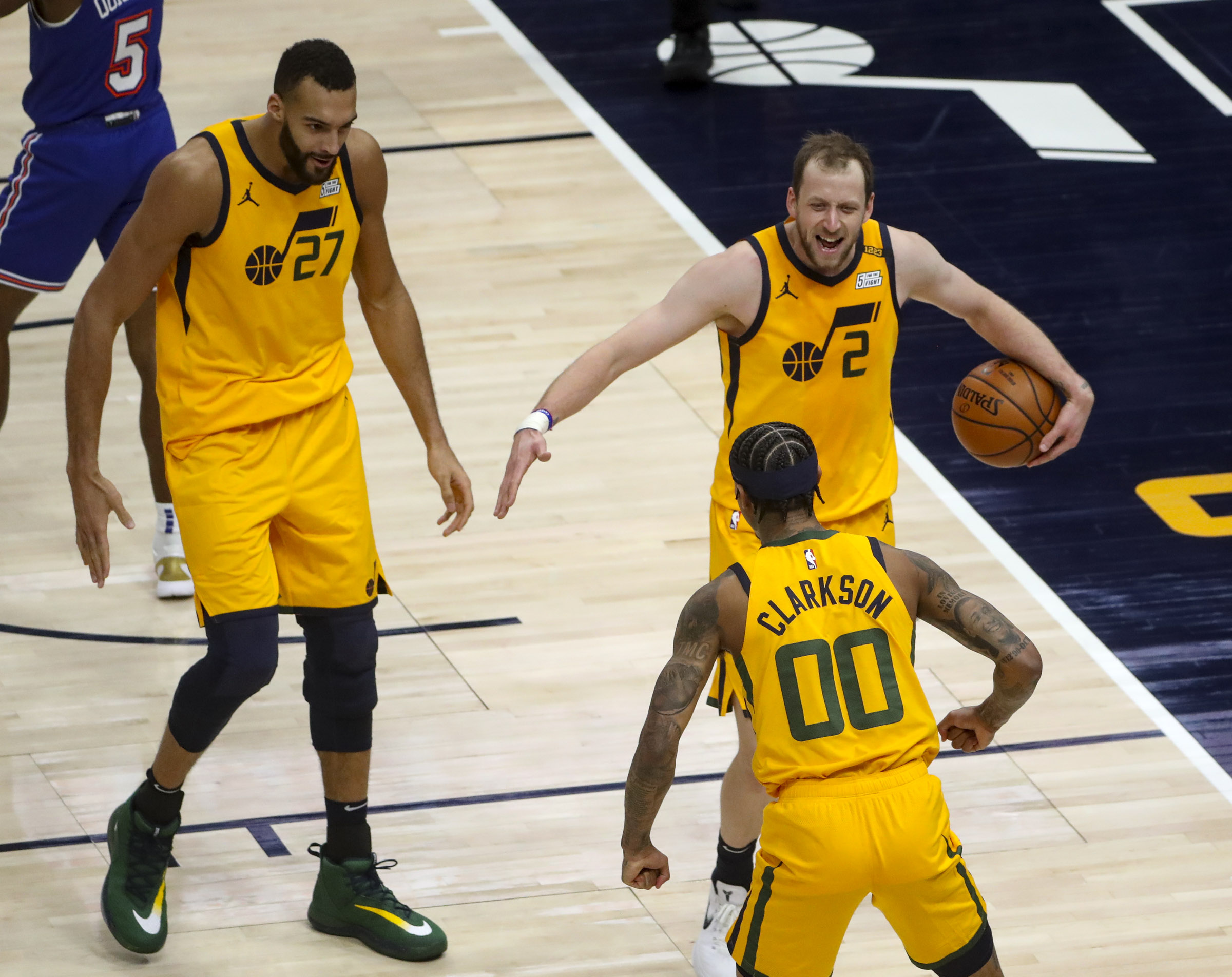 Utah Jazz forward Joe Ingles (2) and Utah Jazz center Rudy Gobert (27) run to Utah Jazz guard Jordan Clarkson (00) after he made an acrobatic shot during the New York Knicks and Utah Jazz NBA basketball game at Vivint Smart Home Arena in Salt Lake City on Tuesday, Jan. 26, 2021.